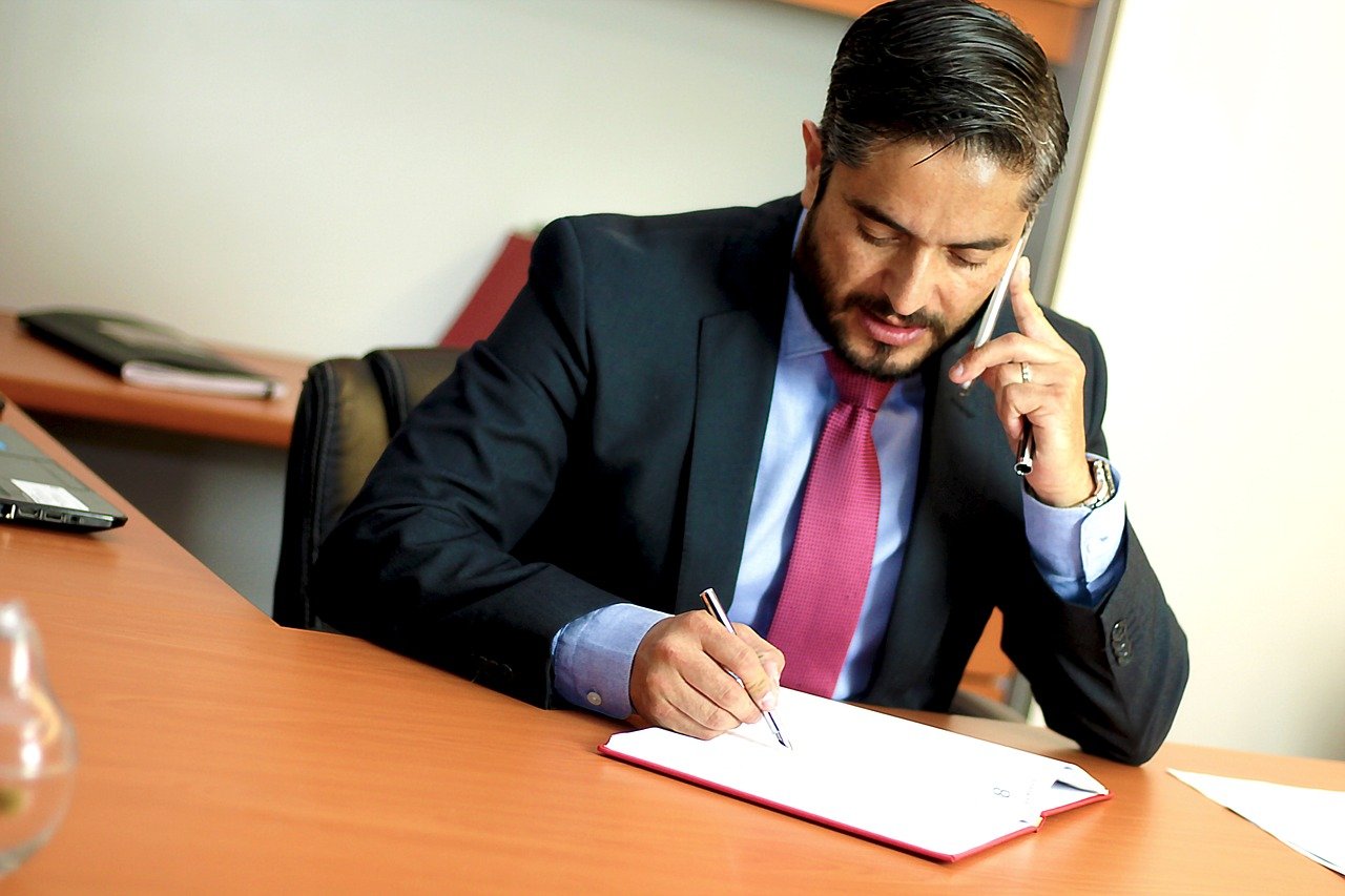 A lawyer at his desk writing and on the phone