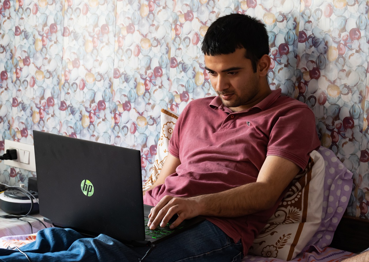 a man on his bed with a laptop