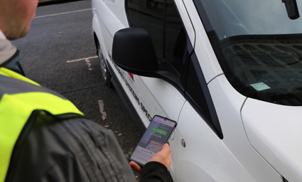 A man with a tablet next to a van