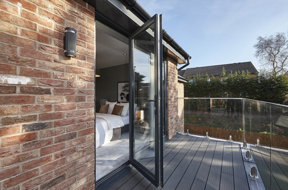 An Aluminium bi-fold door, decking and a glass balcony