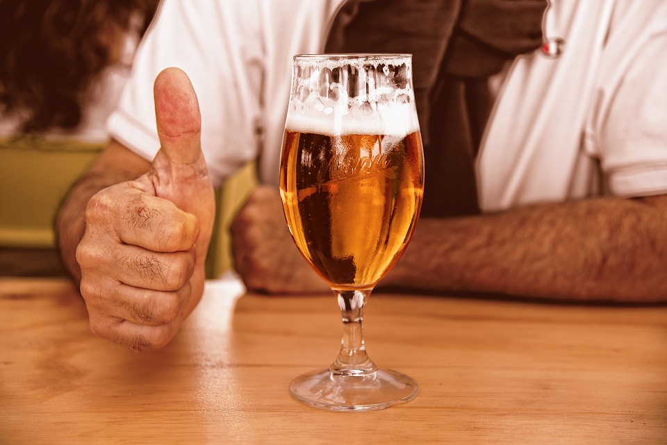 A man with a bint of beer giving the thumbs up