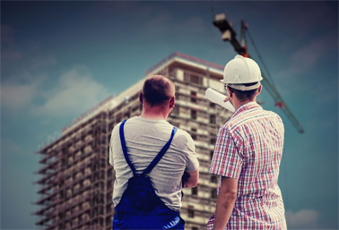 Two construction workers looking up at a building