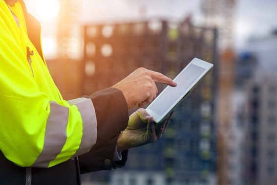 A  man in a high vis jacket holding a tablet