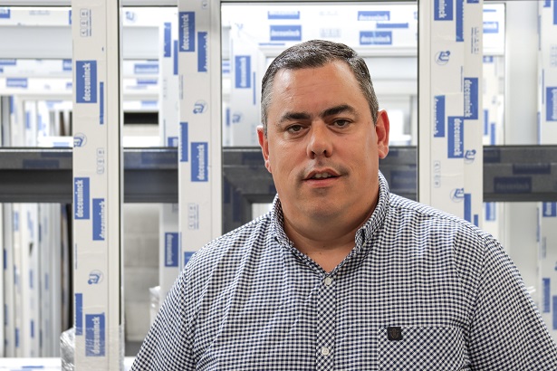 A man in a check shirt with Dececunink windows in the background