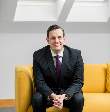 Simon Robinson sitting on a yellow sofa under two skylights