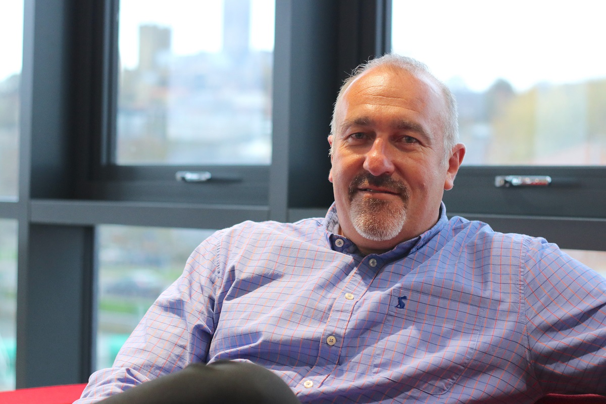 A man in a lilac shirt sitting in an office