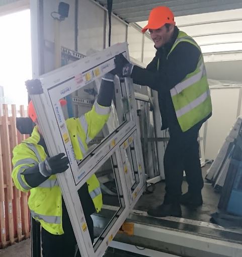 Two mwn unload windows from a van